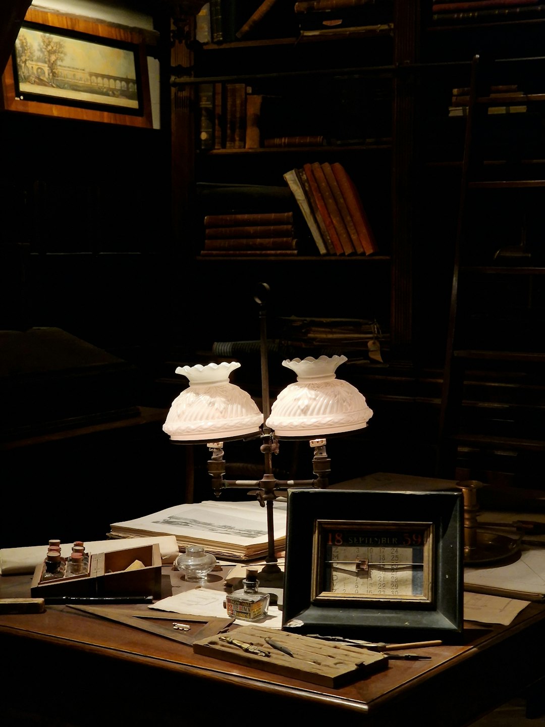 Una lampada a olio illumina una penna d'oca e delle carte su una scrivania.